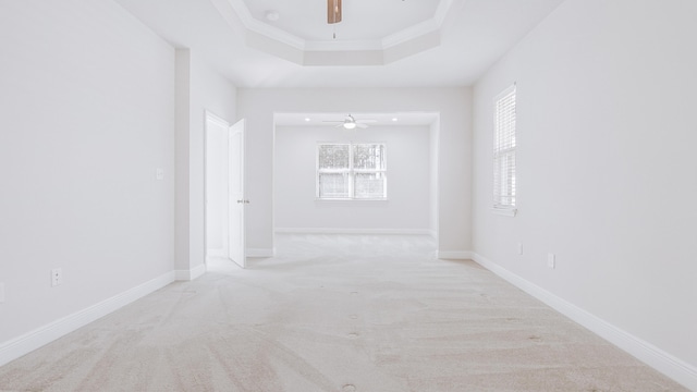 carpeted spare room with ceiling fan, baseboards, and a raised ceiling
