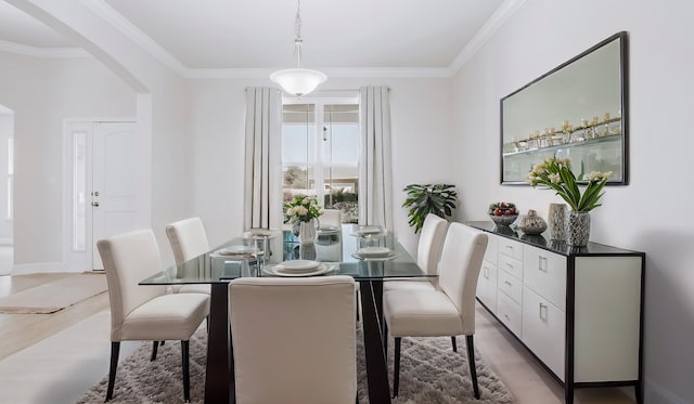 dining area with arched walkways, light wood finished floors, and ornamental molding