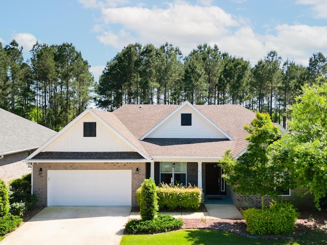 craftsman-style home featuring a shingled roof, driveway, brick siding, and a garage