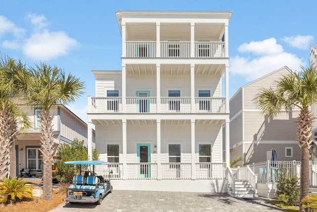 coastal home featuring decorative driveway and covered porch