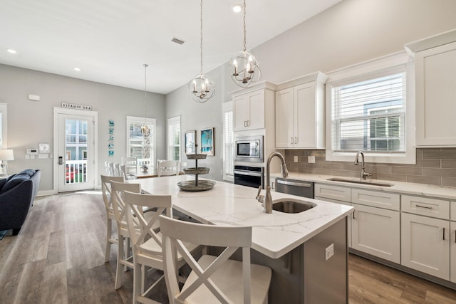 kitchen featuring a sink, decorative backsplash, wood finished floors, and stainless steel appliances