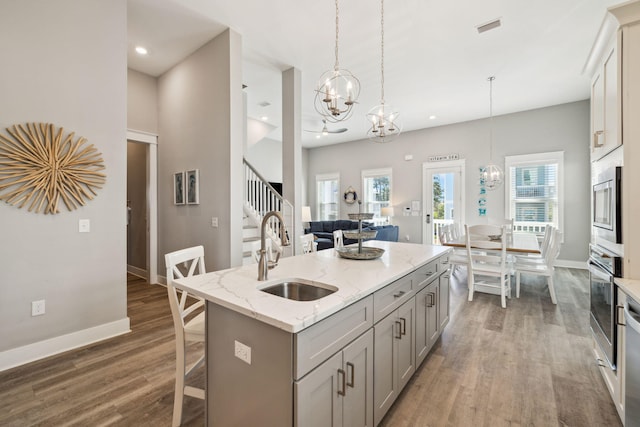 kitchen featuring gray cabinets, a sink, wood finished floors, appliances with stainless steel finishes, and a chandelier