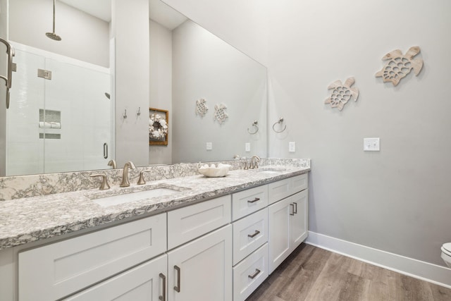 bathroom with wood finished floors, baseboards, a stall shower, and a sink