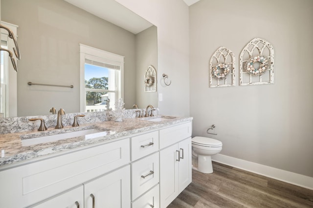 full bathroom with toilet, wood finished floors, baseboards, and a sink