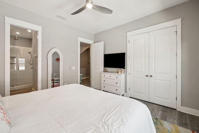 bedroom with wood finished floors, baseboards, visible vents, ensuite bath, and a closet