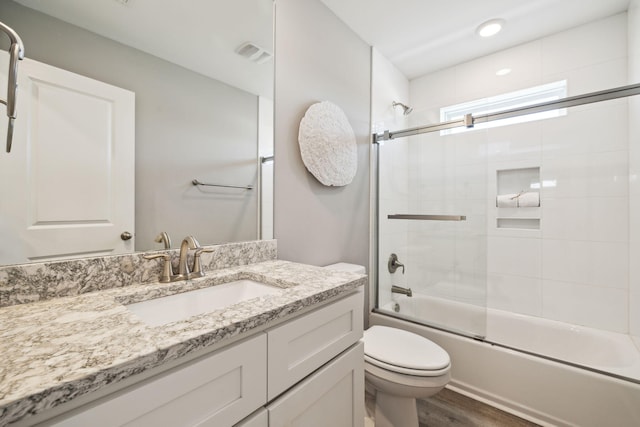 full bathroom featuring vanity, wood finished floors, visible vents, shower / bath combination with glass door, and toilet