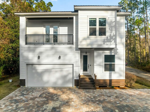 view of front of home with a balcony, a garage, and decorative driveway