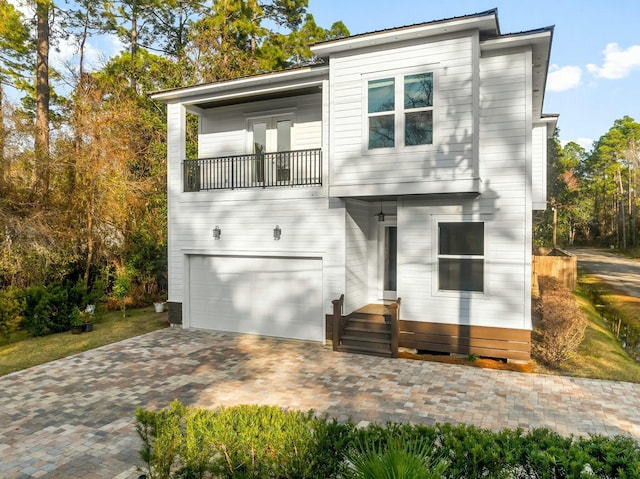 view of front of home with a balcony, a garage, and decorative driveway