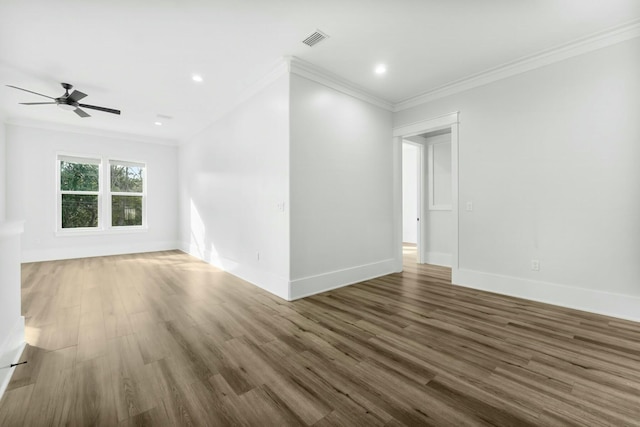 empty room featuring baseboards, crown molding, visible vents, and wood finished floors