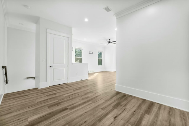 spare room with baseboards, visible vents, ornamental molding, light wood-style floors, and recessed lighting