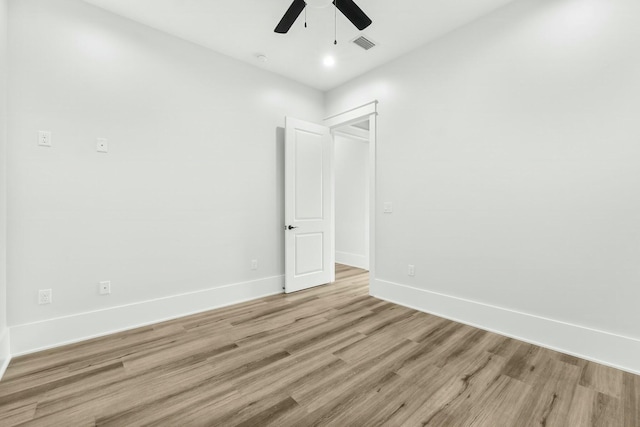 spare room featuring a ceiling fan, light wood-type flooring, visible vents, and baseboards