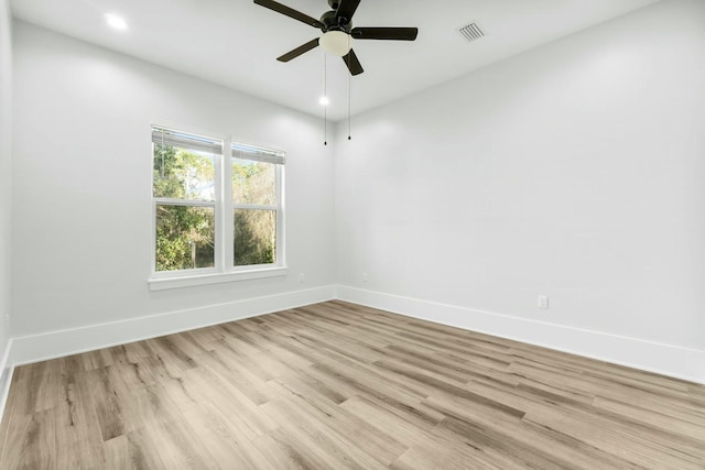 empty room featuring light wood finished floors, baseboards, visible vents, and ceiling fan