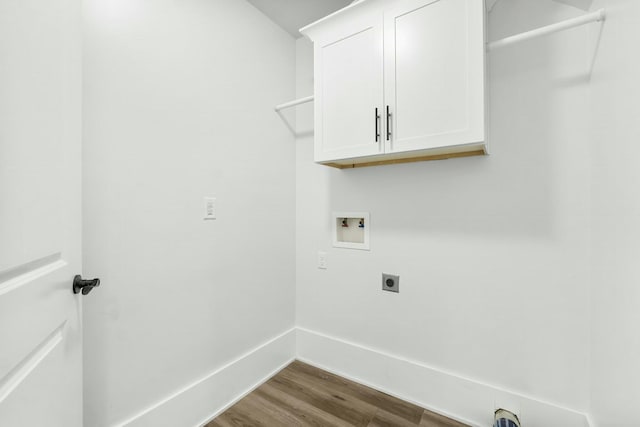 washroom featuring cabinet space, baseboards, dark wood-type flooring, hookup for a washing machine, and hookup for an electric dryer