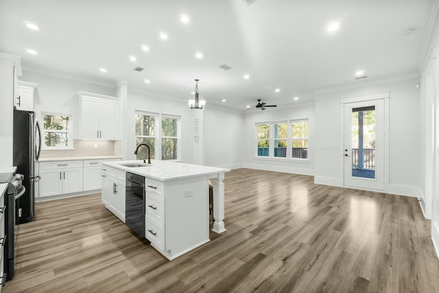 kitchen featuring decorative backsplash, freestanding refrigerator, a kitchen island with sink, a sink, and beverage cooler