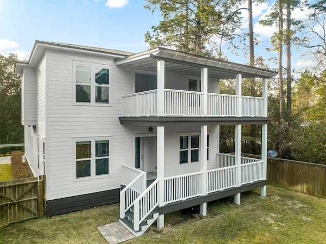 rear view of house featuring a porch, a yard, fence, and a balcony