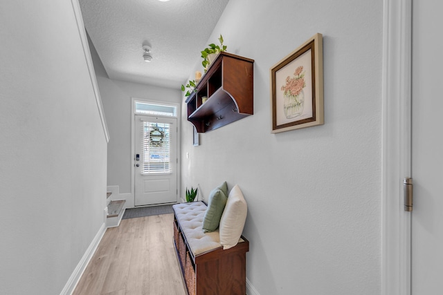 doorway with light wood-style flooring, baseboards, and a textured ceiling