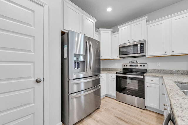 kitchen featuring white cabinets, appliances with stainless steel finishes, light stone counters, light wood-style floors, and recessed lighting