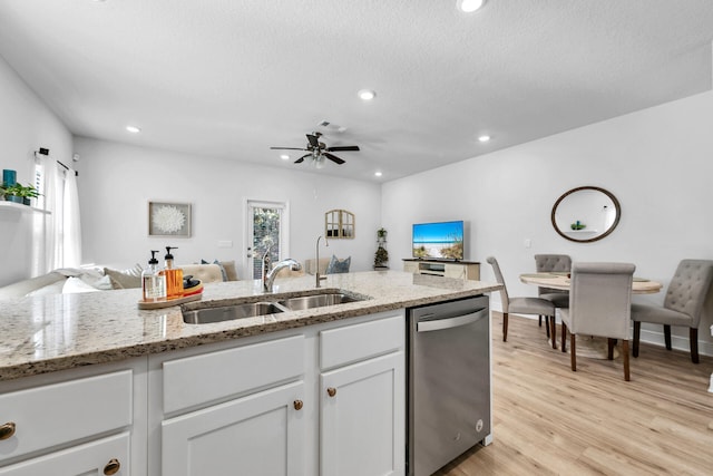 kitchen with light wood finished floors, dishwasher, open floor plan, white cabinetry, and a sink