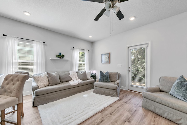 living room with light wood-style flooring, ceiling fan, a textured ceiling, and recessed lighting