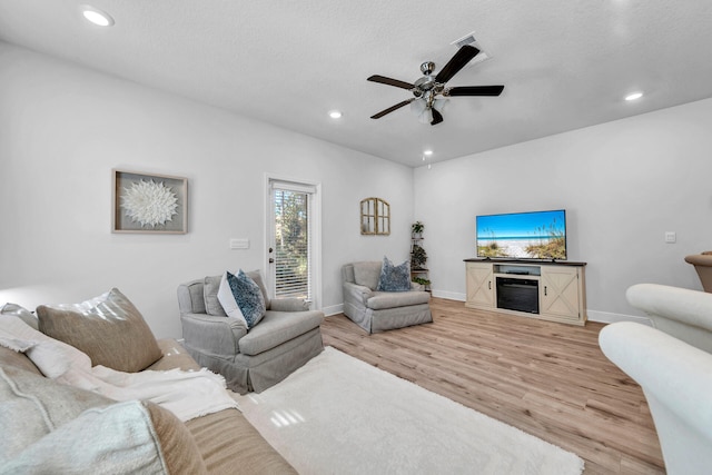 living area with ceiling fan, a textured ceiling, recessed lighting, baseboards, and light wood finished floors