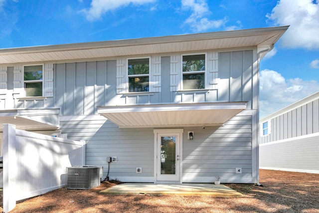 rear view of house with a patio, board and batten siding, and cooling unit