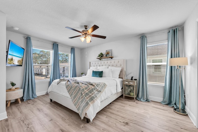 bedroom featuring light wood-type flooring, ceiling fan, baseboards, and a textured ceiling