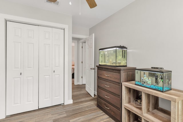 bedroom featuring a ceiling fan, a closet, visible vents, and wood finished floors