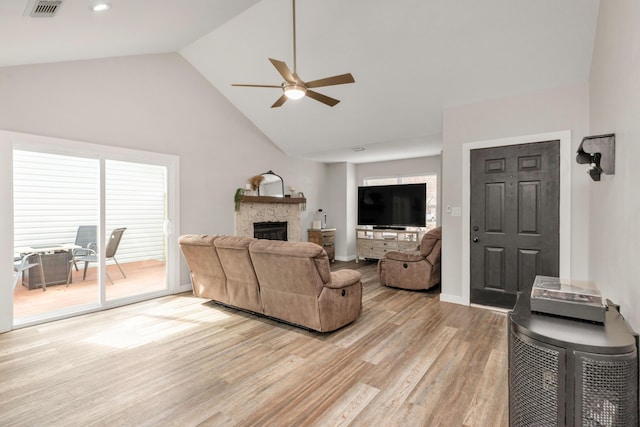 living room featuring a stone fireplace, visible vents, baseboards, a ceiling fan, and light wood-type flooring