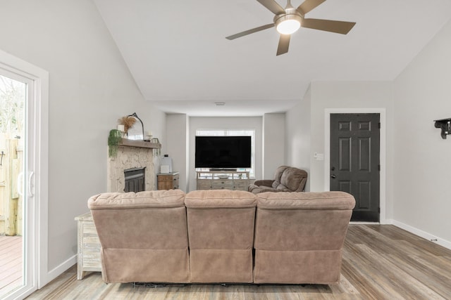 living area featuring plenty of natural light, a fireplace, baseboards, and wood finished floors