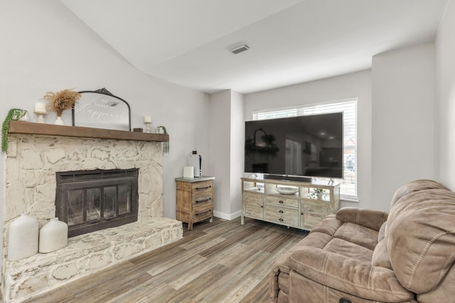 living area featuring a healthy amount of sunlight, a fireplace, baseboards, and wood finished floors