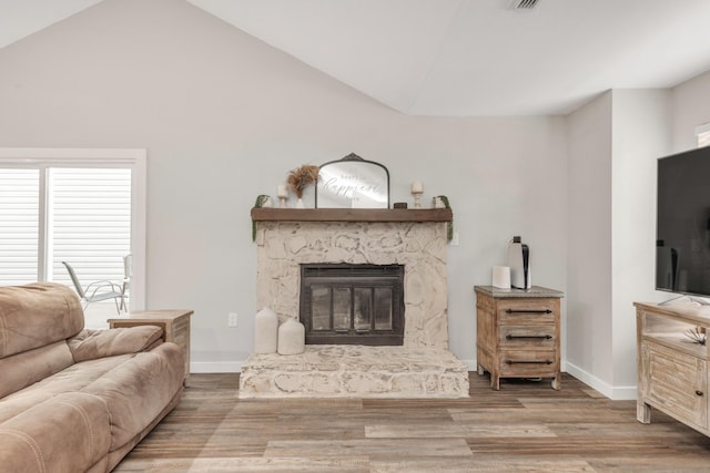 living area featuring vaulted ceiling, a fireplace, wood finished floors, and baseboards