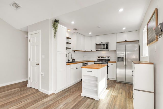 kitchen featuring visible vents, open shelves, butcher block countertops, and appliances with stainless steel finishes