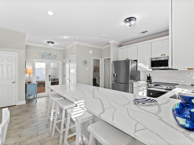 kitchen featuring french doors, tasteful backsplash, visible vents, appliances with stainless steel finishes, and white cabinets