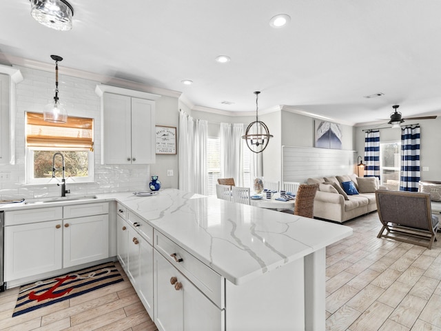 kitchen featuring a peninsula, wood finish floors, a sink, and a wealth of natural light