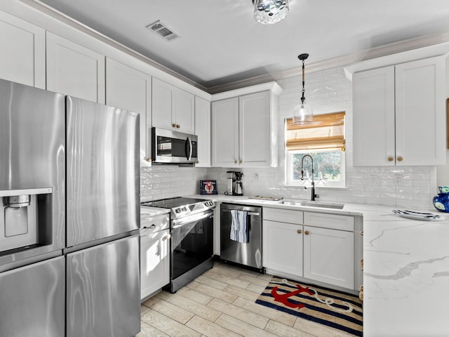 kitchen featuring stainless steel appliances, a sink, visible vents, white cabinets, and decorative backsplash