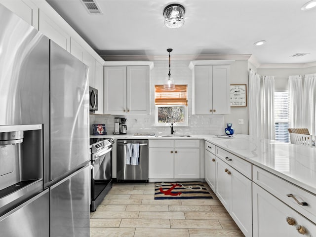 kitchen featuring white cabinets, appliances with stainless steel finishes, a wealth of natural light, and decorative backsplash