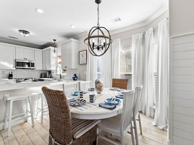 dining room with ornamental molding, light wood-type flooring, and visible vents