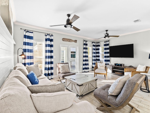 living room featuring french doors, crown molding, visible vents, light wood-style floors, and a ceiling fan