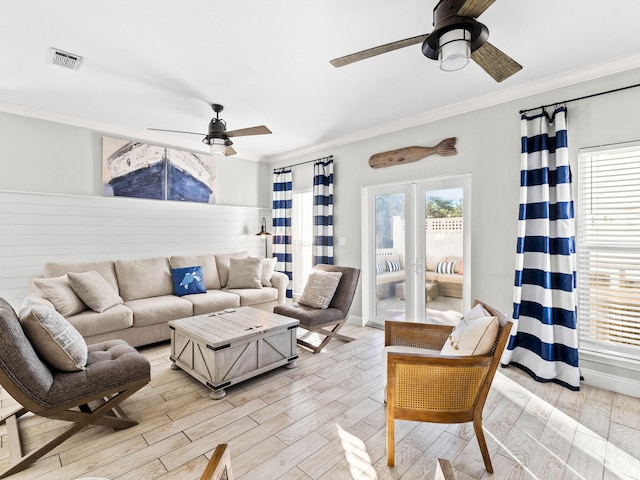 living area featuring crown molding, light wood finished floors, visible vents, a ceiling fan, and baseboards