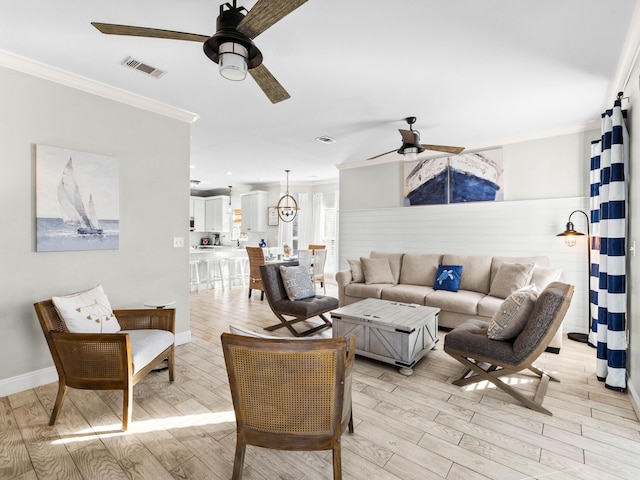 living room with a ceiling fan, light wood-type flooring, visible vents, and crown molding