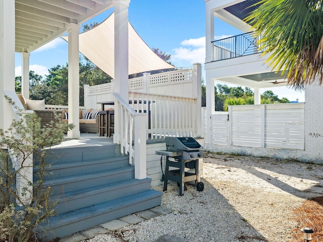 view of patio with grilling area, fence, and a balcony