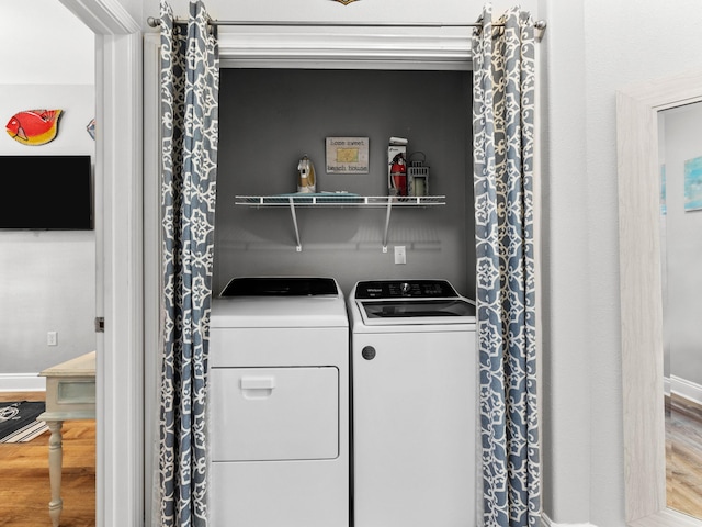 laundry area featuring laundry area, baseboards, washer and clothes dryer, and wood finished floors