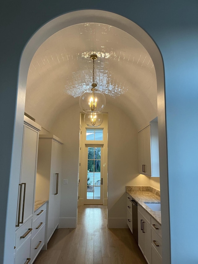 bathroom with hardwood / wood-style floors, baseboards, and vaulted ceiling