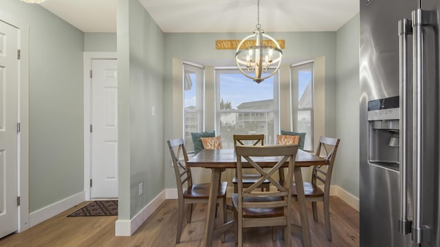 dining room with breakfast area, an inviting chandelier, wood finished floors, and baseboards