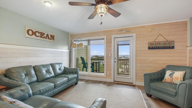 living area with wood finished floors, a ceiling fan, and wooden walls