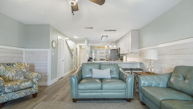 living area with baseboards, light wood-style flooring, visible vents, and a ceiling fan