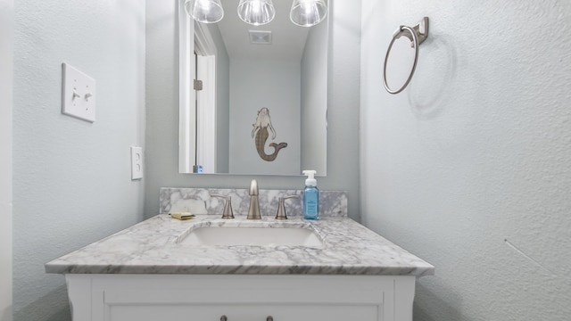 bathroom with a textured wall, visible vents, and vanity