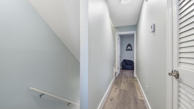 corridor featuring baseboards and light wood finished floors