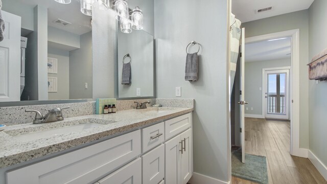 bathroom featuring wood finished floors, a sink, visible vents, and baseboards