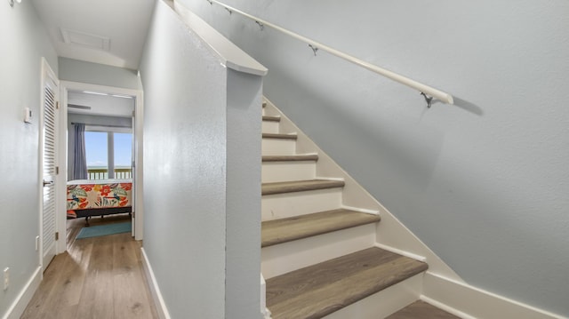 stairs with wood finished floors, attic access, and baseboards